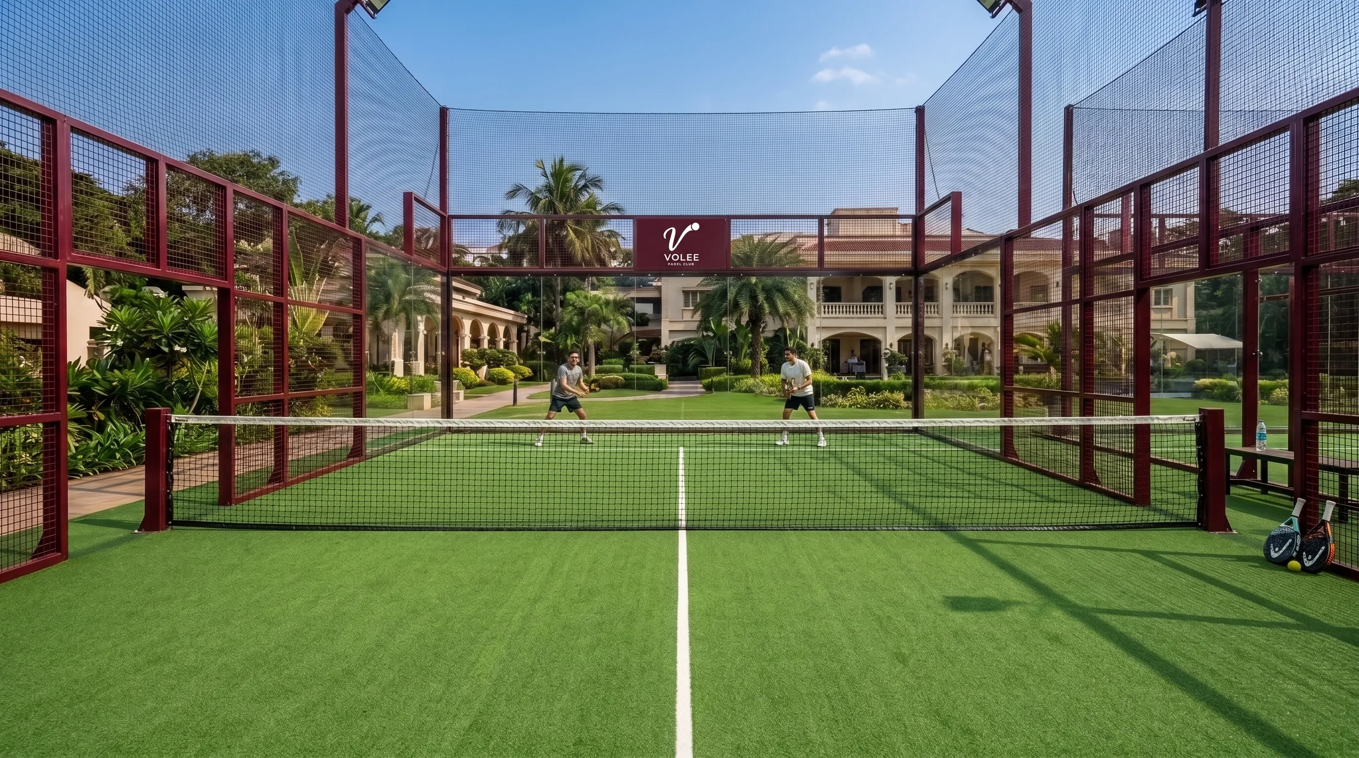 Two players on a padel court framed in maroon, palms and the clubhouse behind